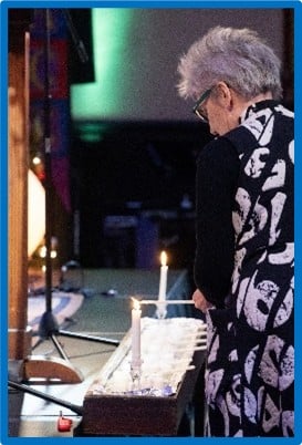 Community member lighting candle at homeless vigil