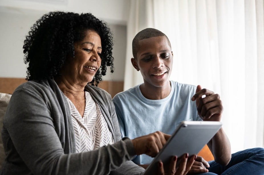 A mother and son smile while viewing health information on a tablet, representing Community Health Center's accessible digital care and patient engagement.